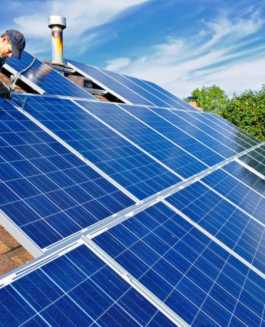 Man installing alternative energy photovoltaic solar panels on roof